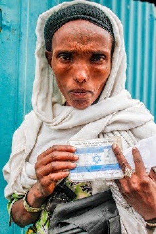 An Ethiopian Jewish woman holds up her Israeli identification card after being cleared to immigrate to the Jewish homeland. This album documents the final mass immigration of Ethiopian Jews to Israel, a process which has dated back to the 1970s. Gondar, Ethiopia, 2013